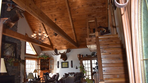 A rustic interior with wooden beams, a fireplace, and a staircase. - Bear Creek Lodge Cabin Resort (Walnut Shade)