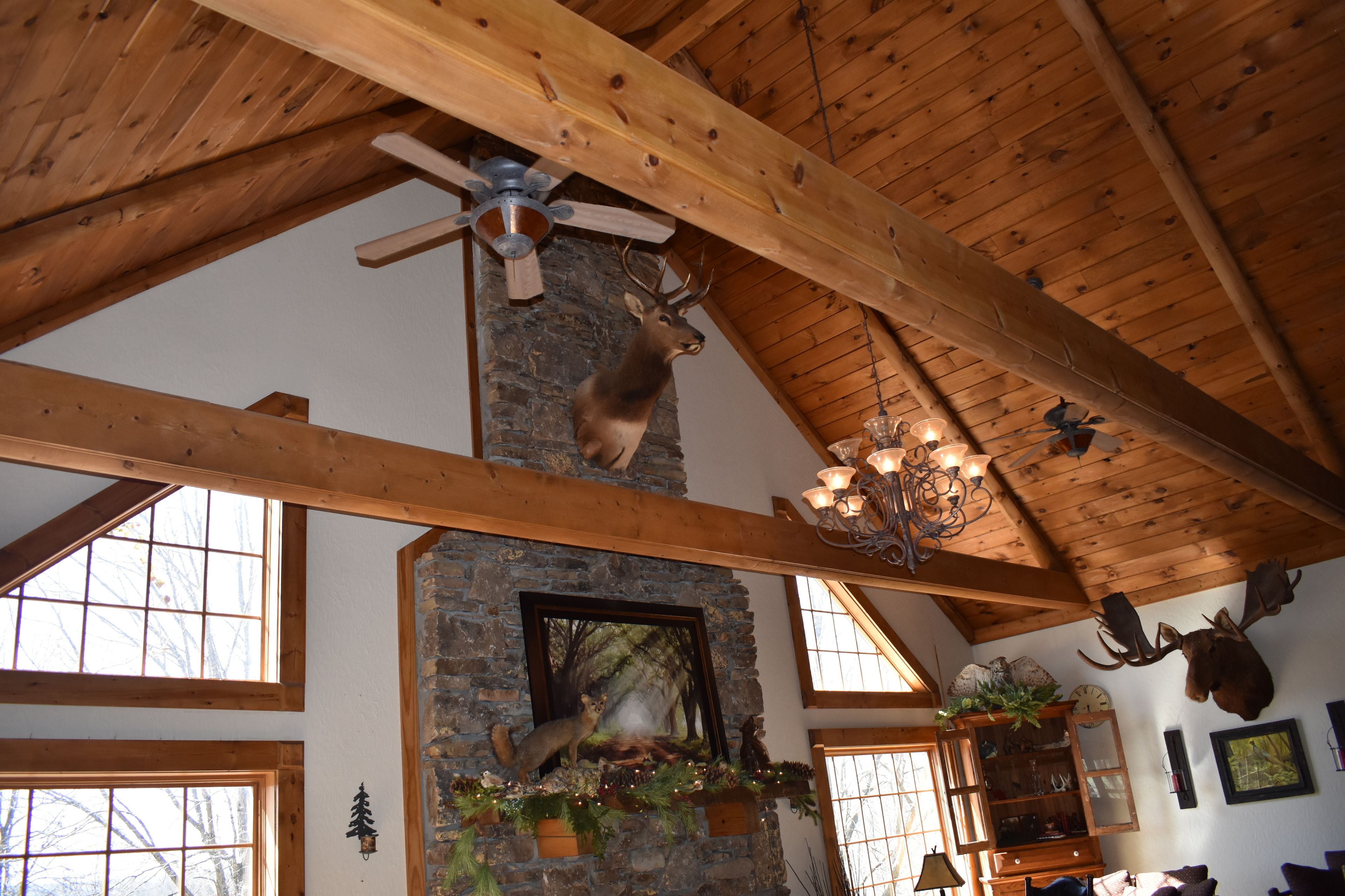 A rustic interior with a stone fireplace, wooden beams, and a deer mounted on the wall.