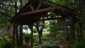 A wooden gazebo with stone pathways and a small pond, surrounded by lush greenery and potted plants. - Bear Creek Lodge Cabin Resort (Walnut Shade)