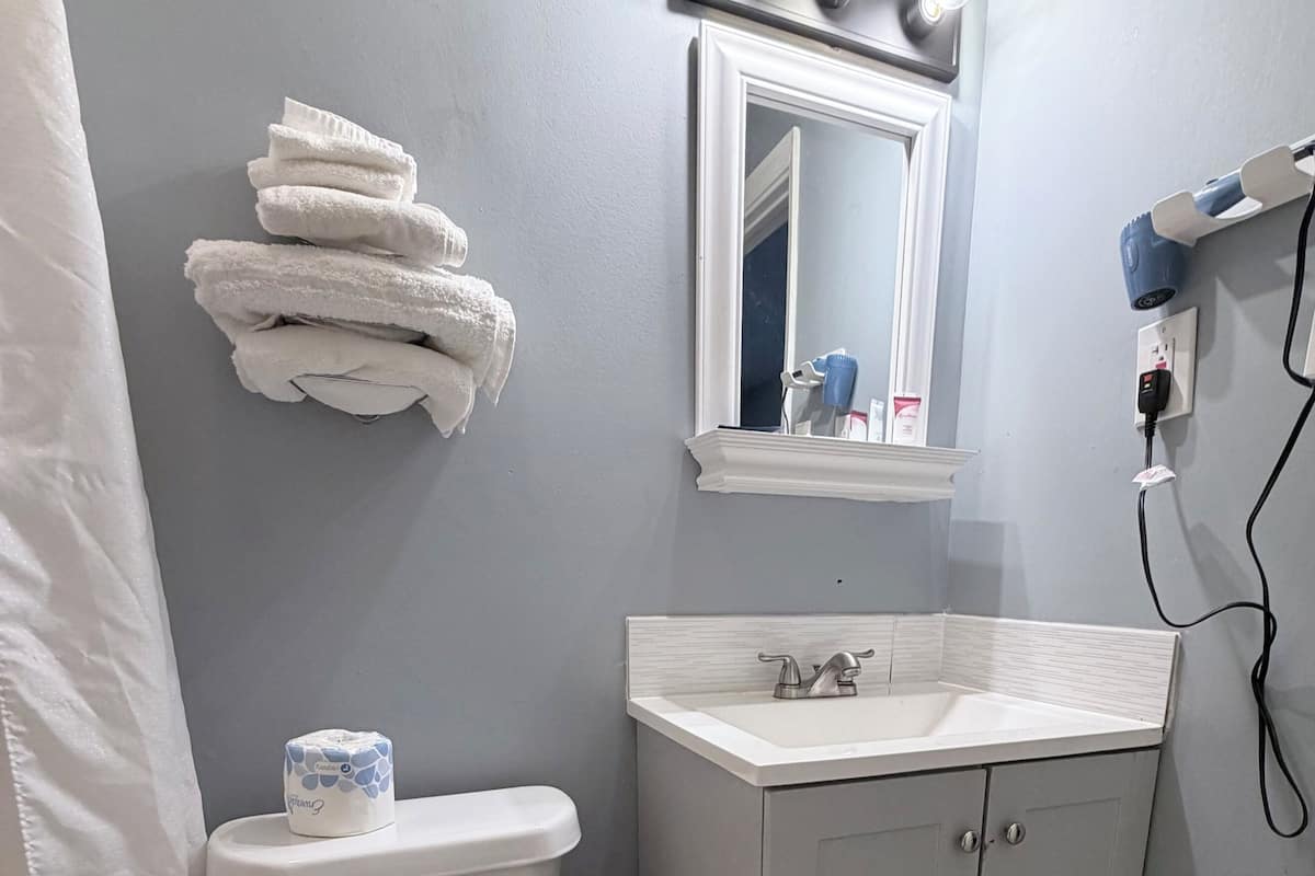 A bathroom with a toilet, sink, vanity, and a towel rack.