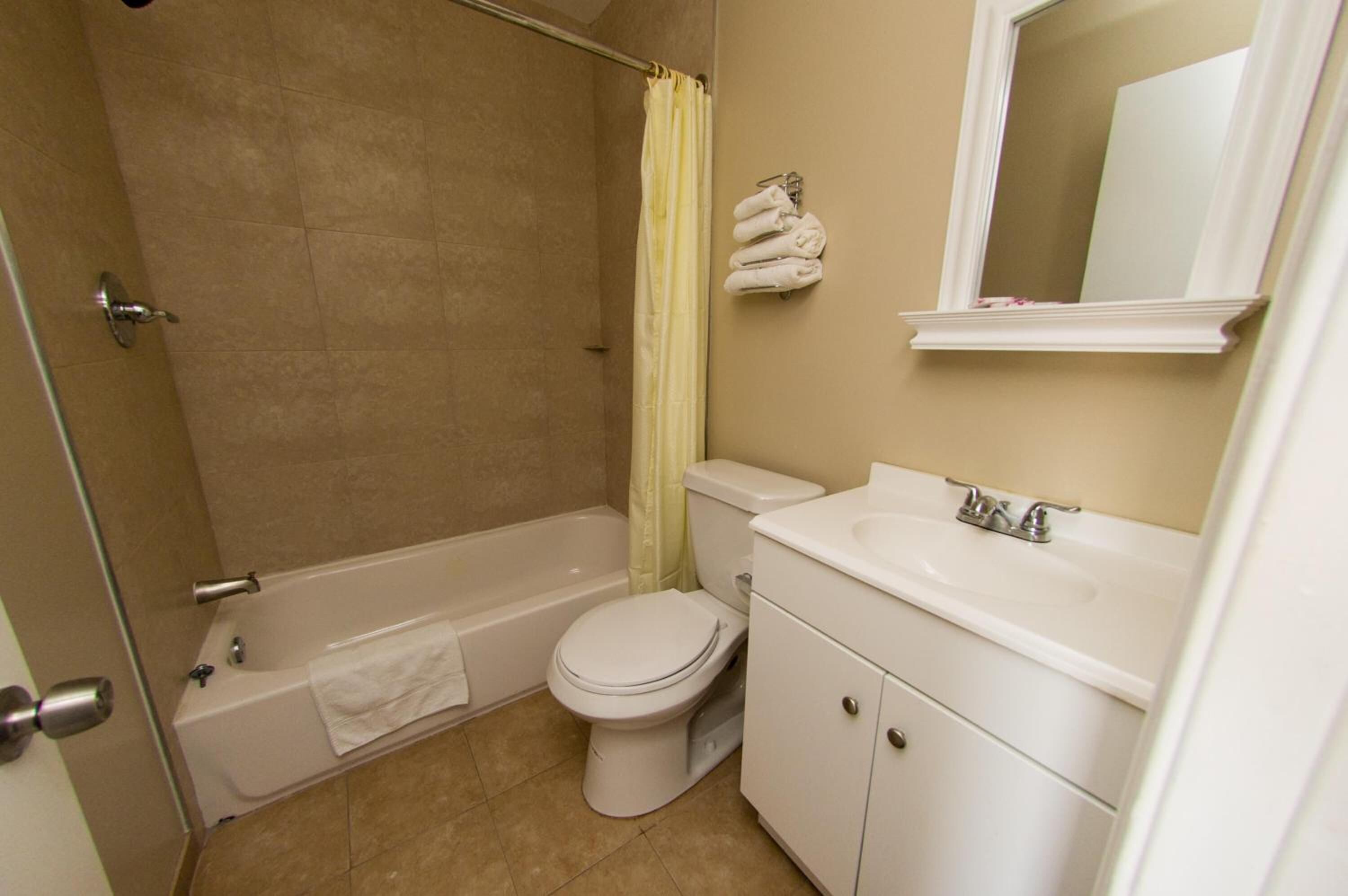 A bathroom with a bathtub, toilet, sink, and a mirror.