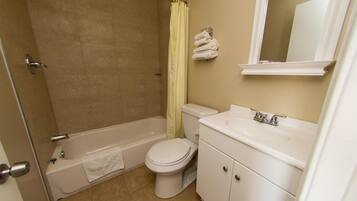 A bathroom with a bathtub, toilet, sink, and a mirror.