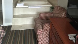 A bathroom with a bathtub, a mirror, and a wooden dresser. - Scottish Inn and Suites (Bensalem)