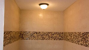 A bathroom with a large bathtub, tiled walls, and a small step leading up to the tub. - Scottish Inn and Suites (Bensalem)