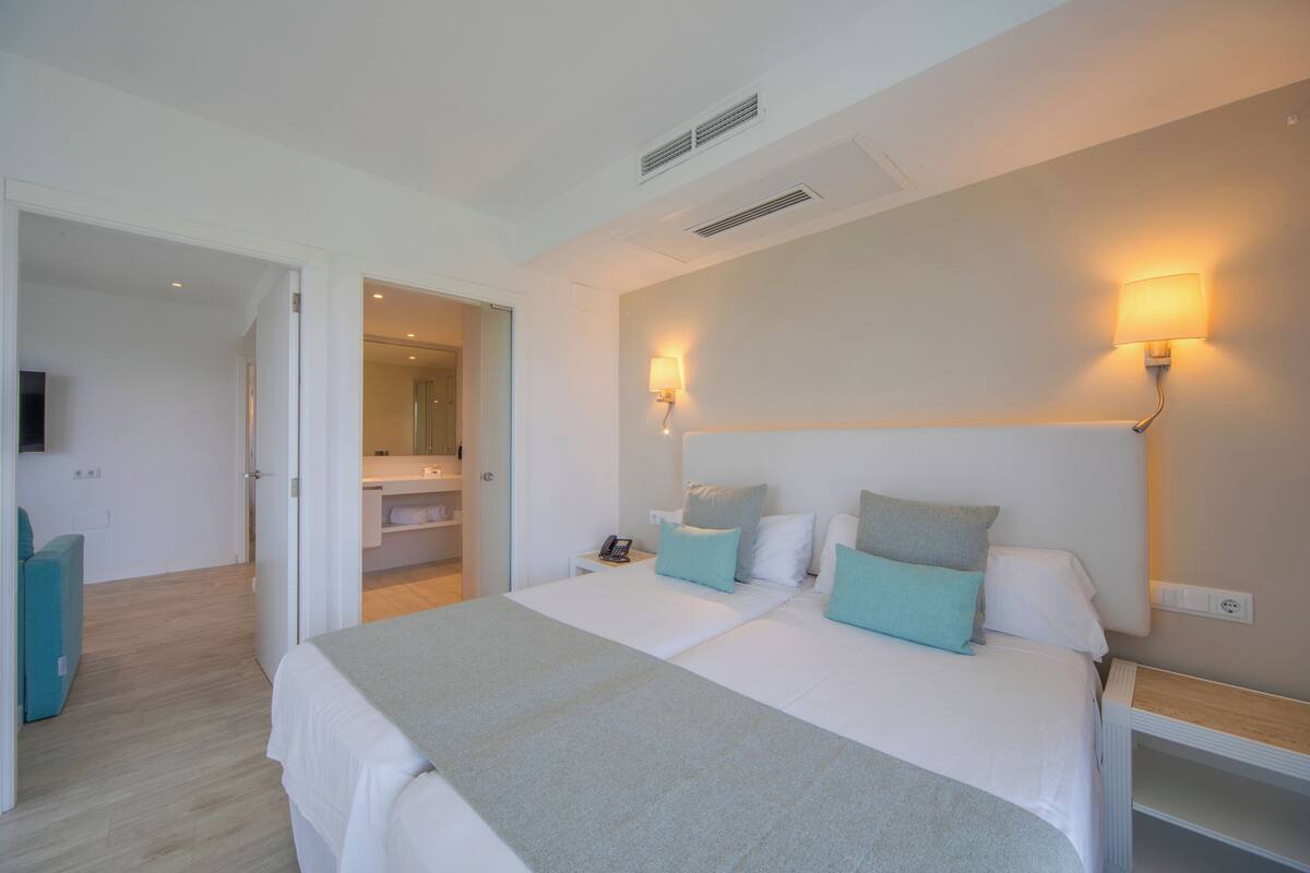 A hotel room with two beds, a bathroom, and a TV.