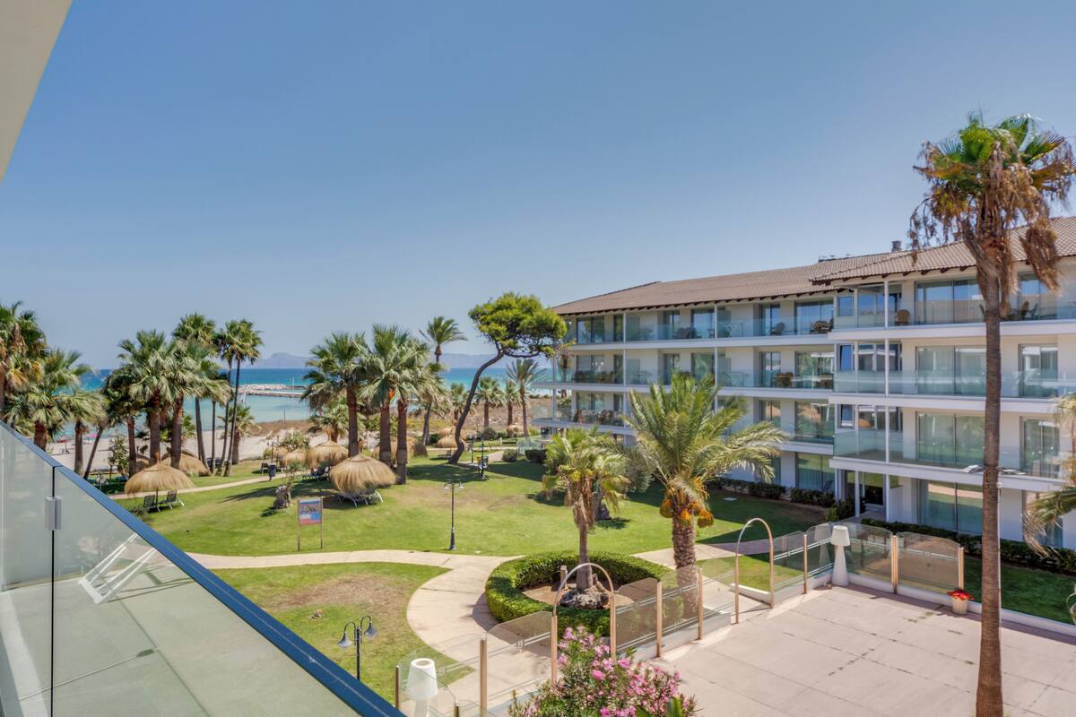 A hotel with a pool, palm trees, and a view of the ocean.