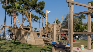 A wooden playground structure with climbing elements and a slide. - Playa Esperanza Resort (Muro)