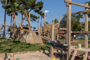 A wooden playground structure with climbing elements and a slide. - Playa Esperanza Resort (Muro)