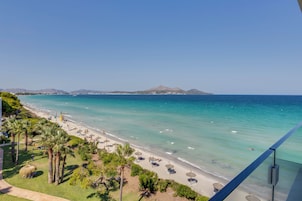 Una playa con agua turquesa cristalina, palmeras y sombrillas.