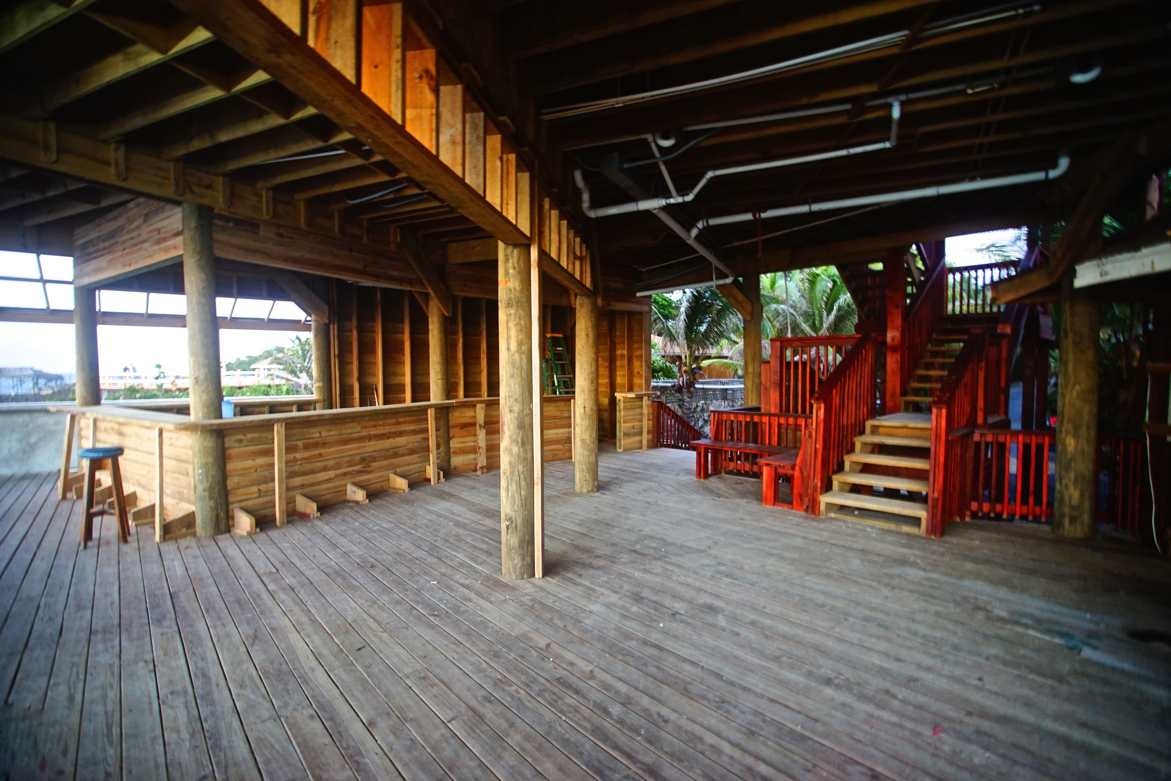 Une terrasse en bois avec un escalier et un espace salon, donnant sur une étendue d’eau.
