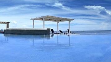 Una piscina al aire libre, sillones reclinables de piscina