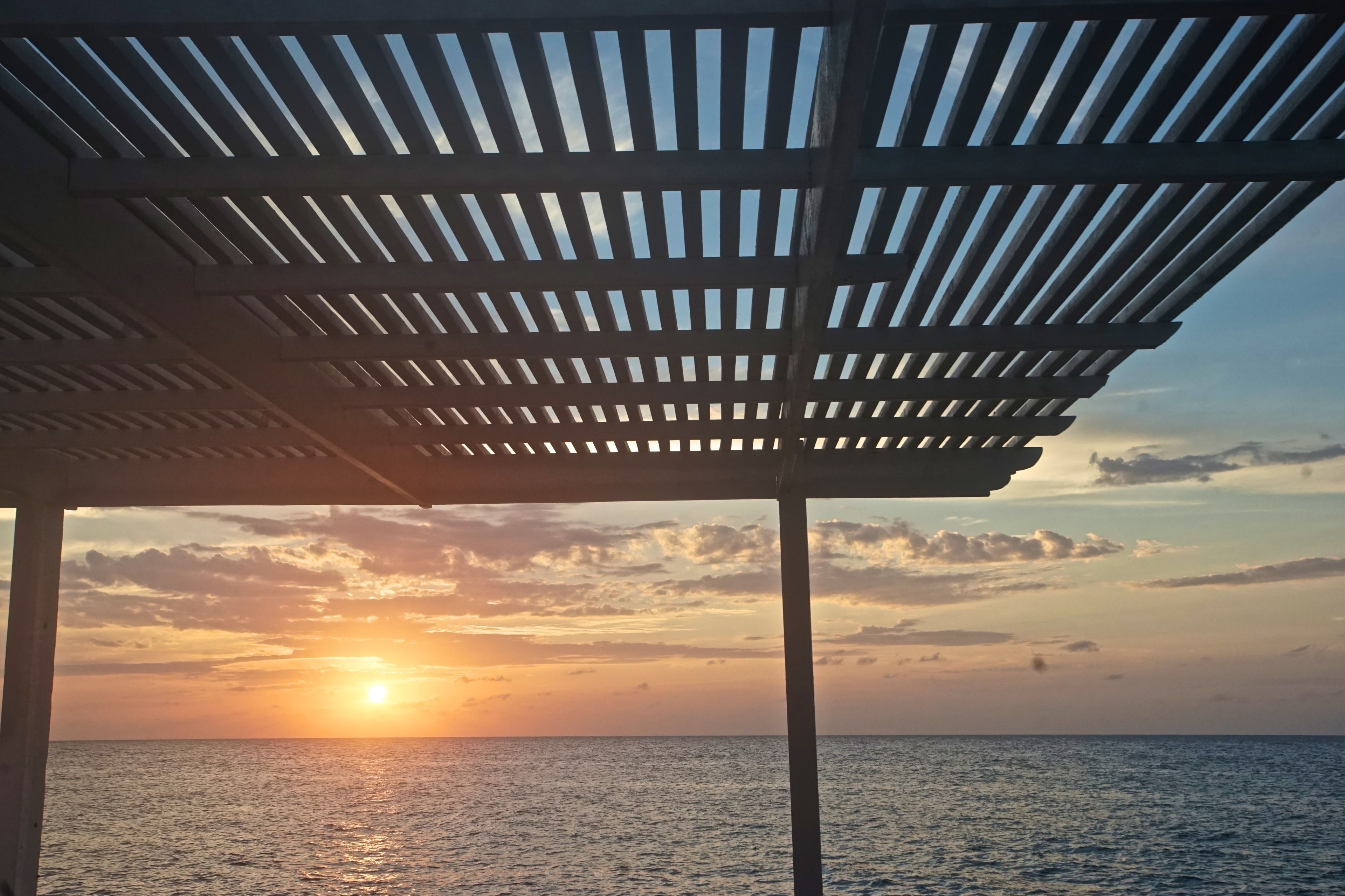 Une vue sur la plage avec une structure de pergola en bois.