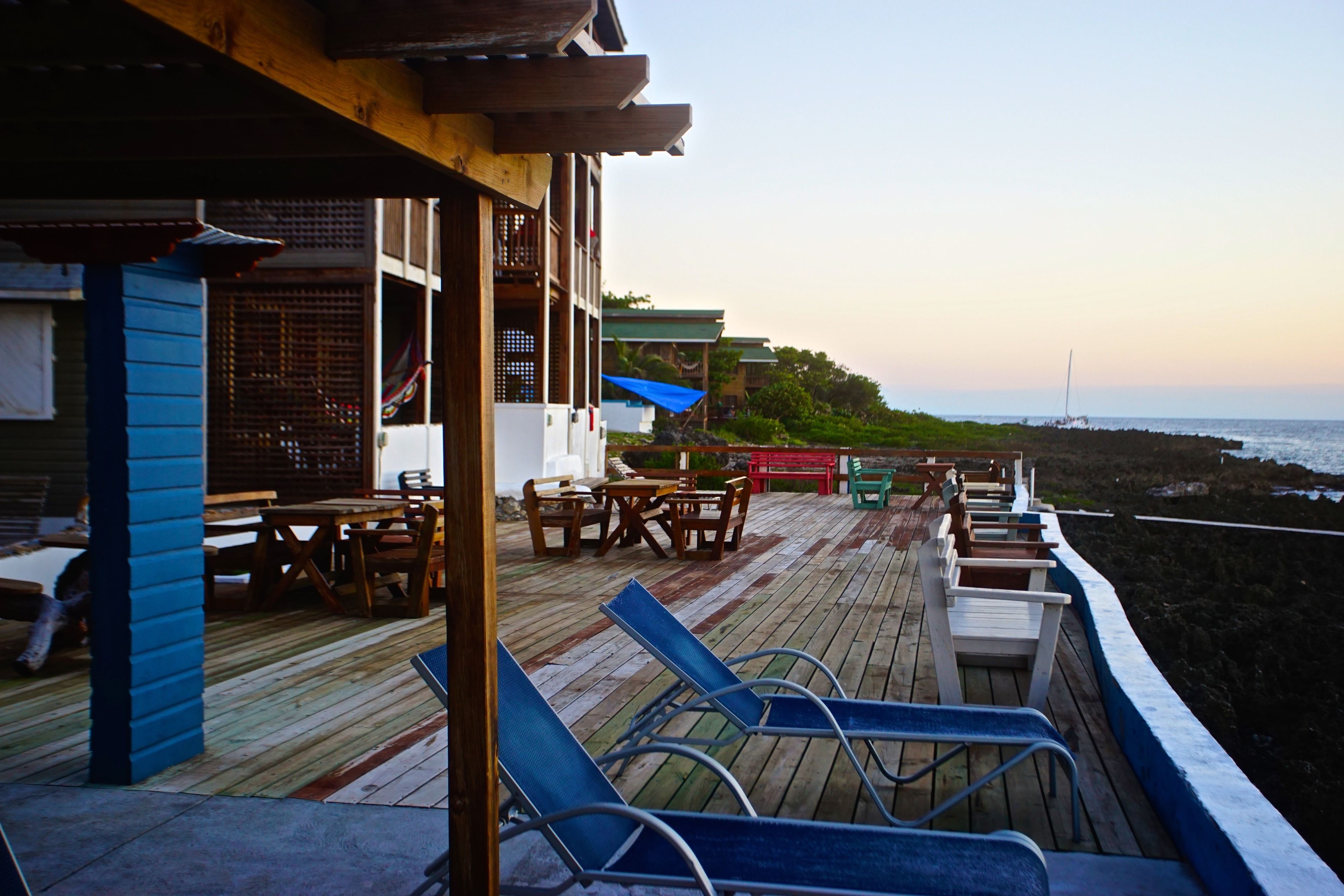 A wooden deck with lounge chairs, a table, and a covered seating area overlooking the ocean.