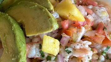 A bowl of seafood salad with avocado slices and a side of lettuce.