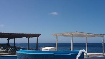 Relax by the pool surrounded by a shaded pergola, overlooking the ocean.