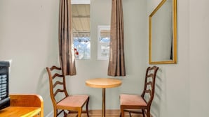 A room with a round table, two wooden chairs, a mirror, and a window with curtains. - Park Motel (Toronto)