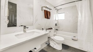 Um banheiro com duas pias, vaso sanitário, banheira e chuveiro.