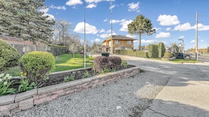Um bairro residencial com uma casa de dois andares, gramado bem cuidado e entrada de automóveis em cascalho.