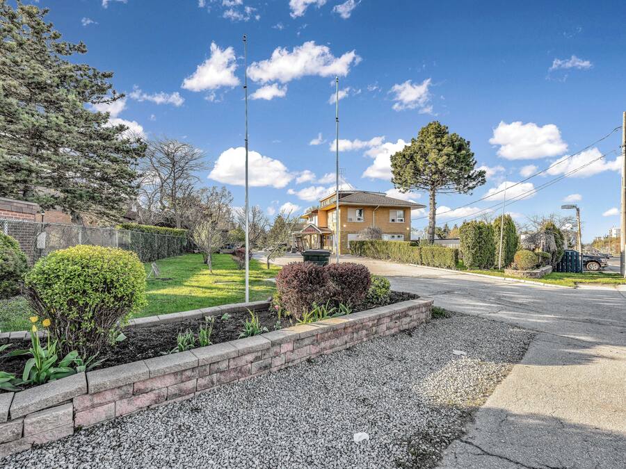Un barrio residencial con una casa de dos pisos, césped bien cuidado y entrada de grava.