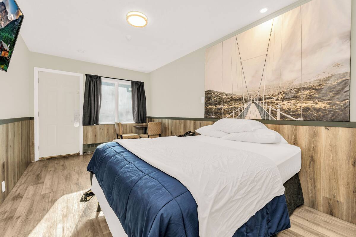 Habitación de hotel con cama, escritorio y ventana grande.