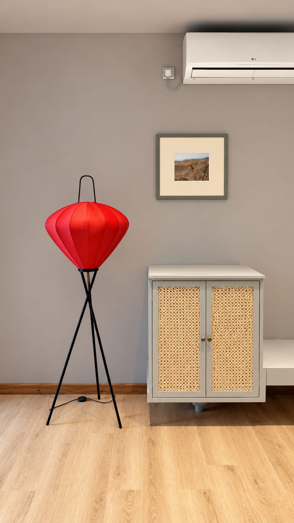 Una habitación con una lámpara roja de pie, un cuadro en la pared y un mueble con frente de tejido.