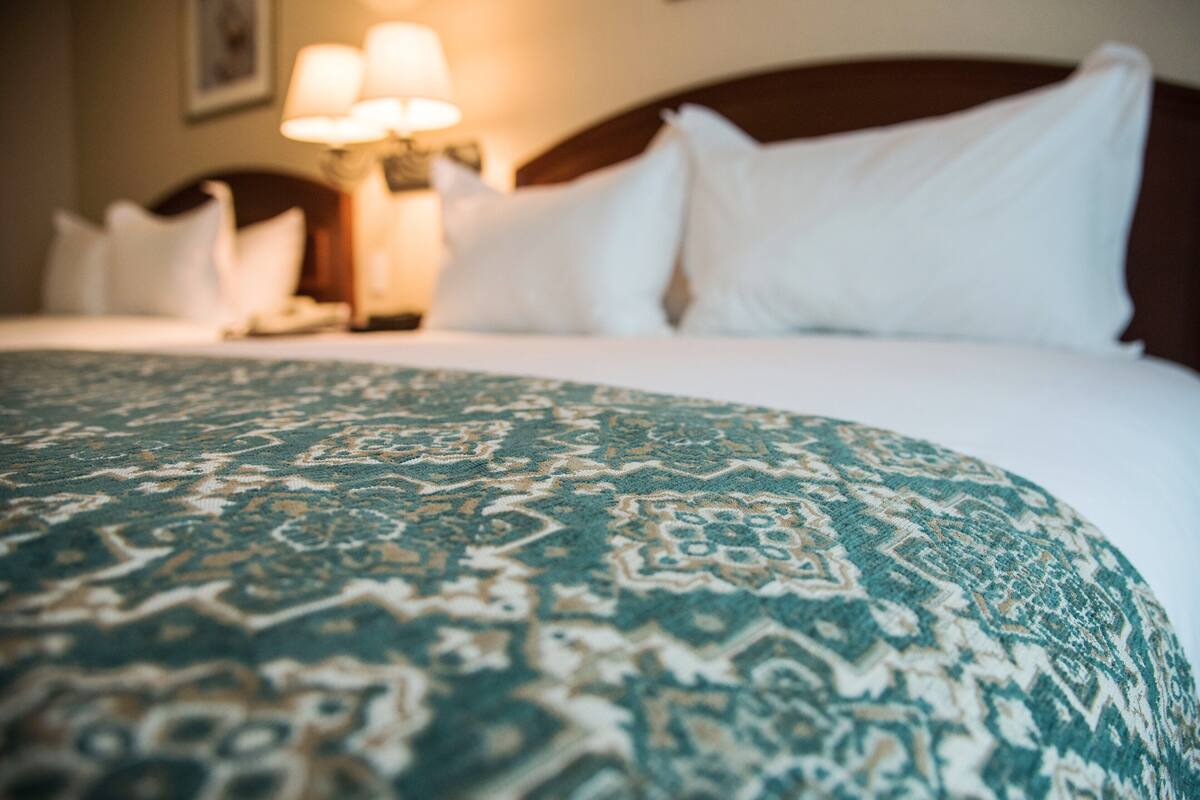 A bed with a patterned bedspread and white pillows.