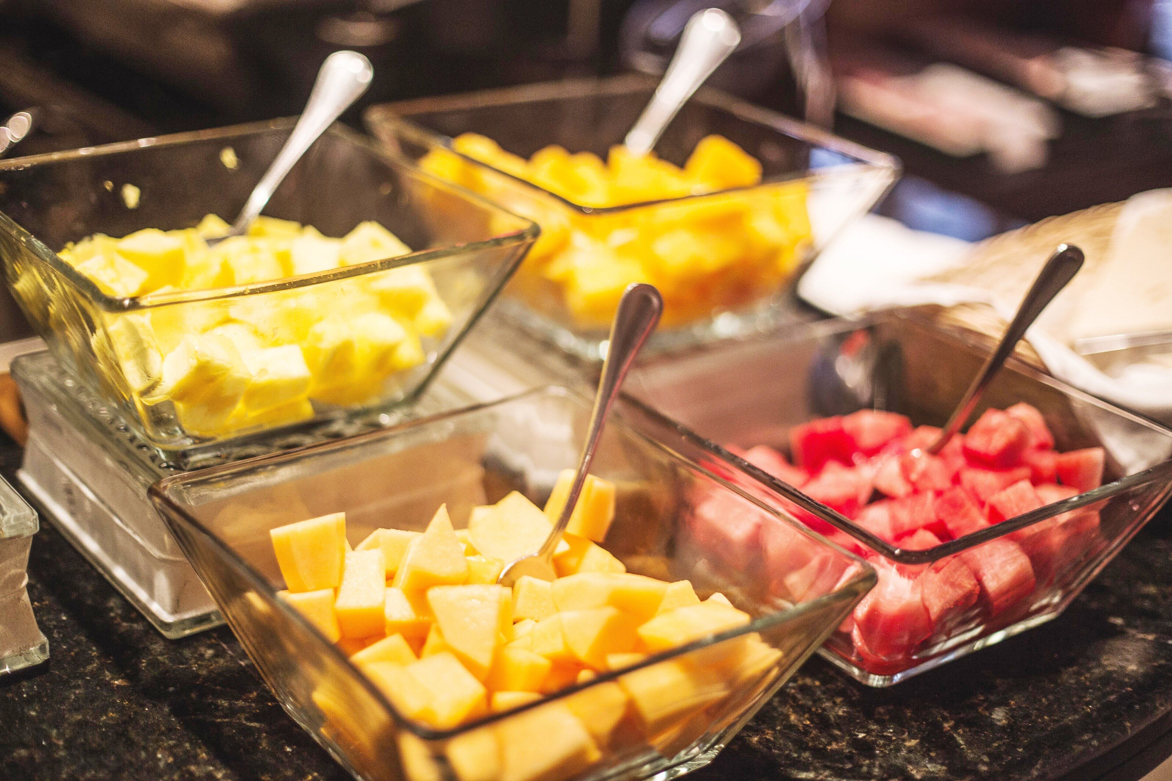 Tres recipientes de vidrio con fruta cortada en cubos, cada uno con una cuchara.