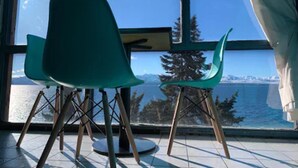Una habitación con dos sillas verdes y un ventanal con vistas al agua y a árboles.