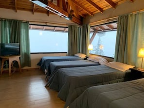 Una habitación con dos camas, televisión y ventana con cortinas.