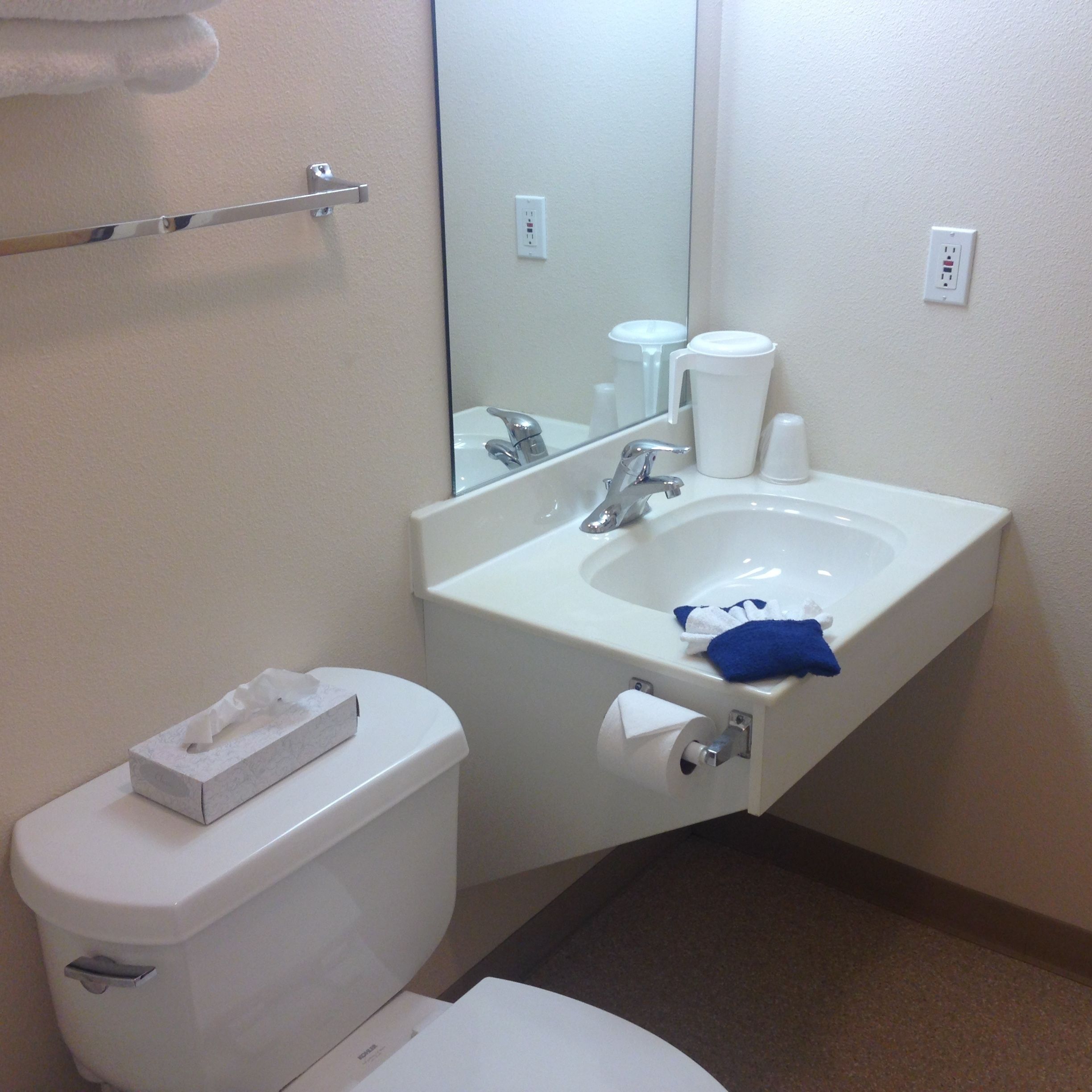 A bathroom with a toilet, sink, and mirror.