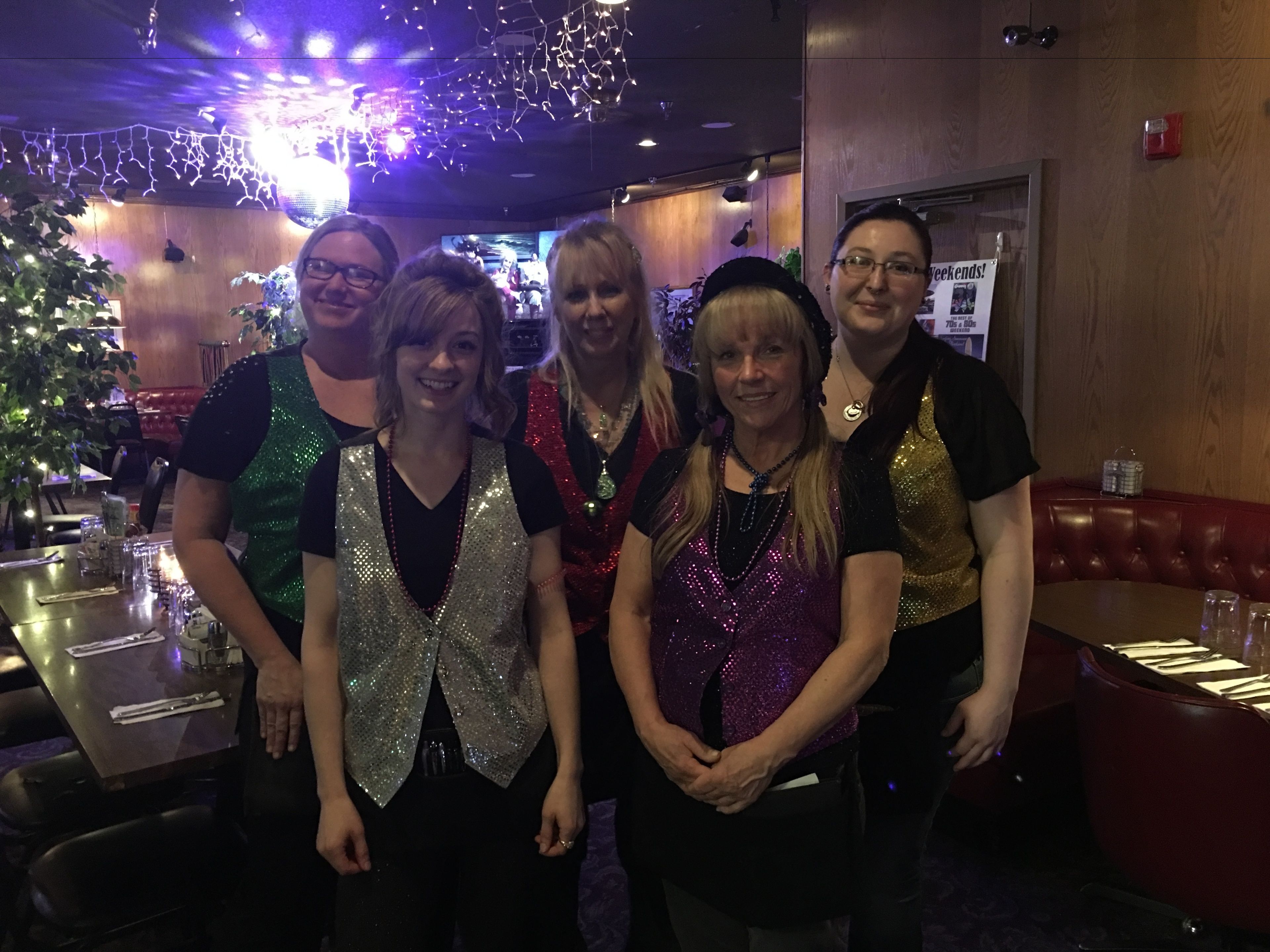 A group of people standing in a restaurant with wooden walls and a Christmas tree in the background.