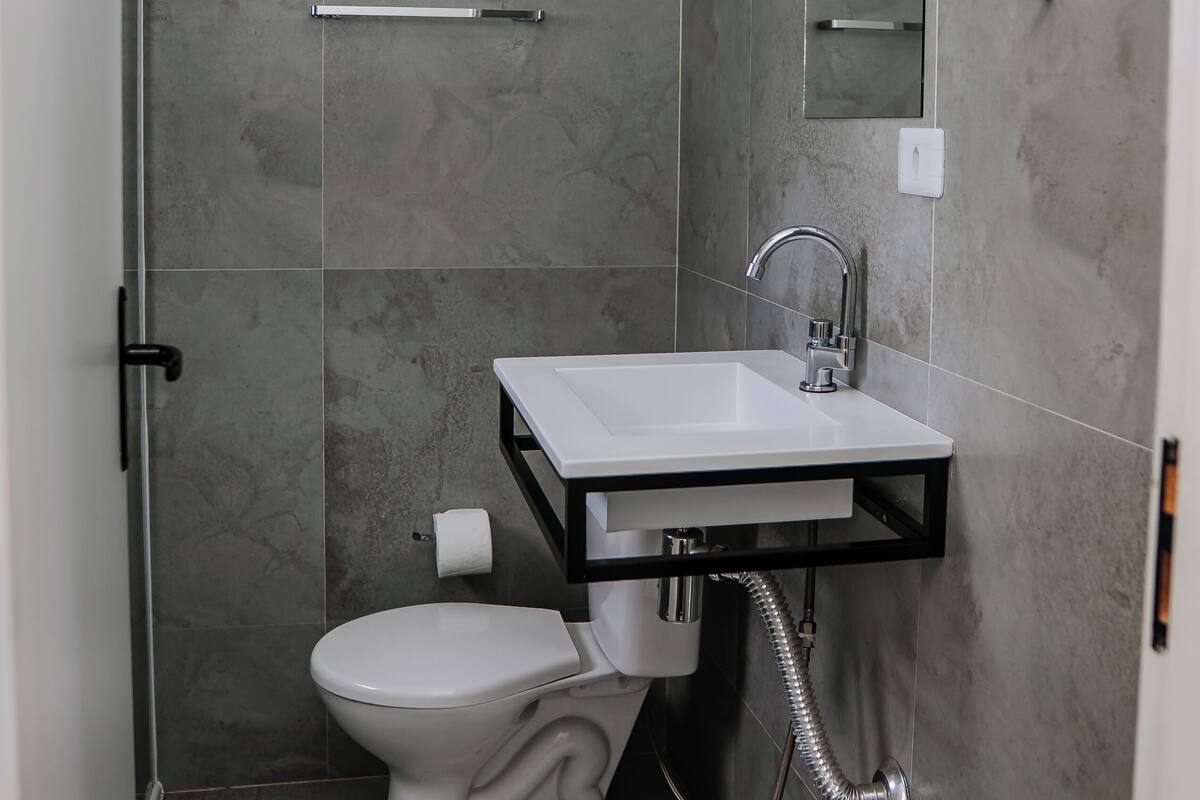 A modern bathroom with a toilet, sink, and shower.