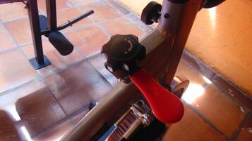 A stationary exercise bike with a red handlebar and a control knob.