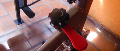 Bicicleta estatica amb manillar vermell i un comandament.