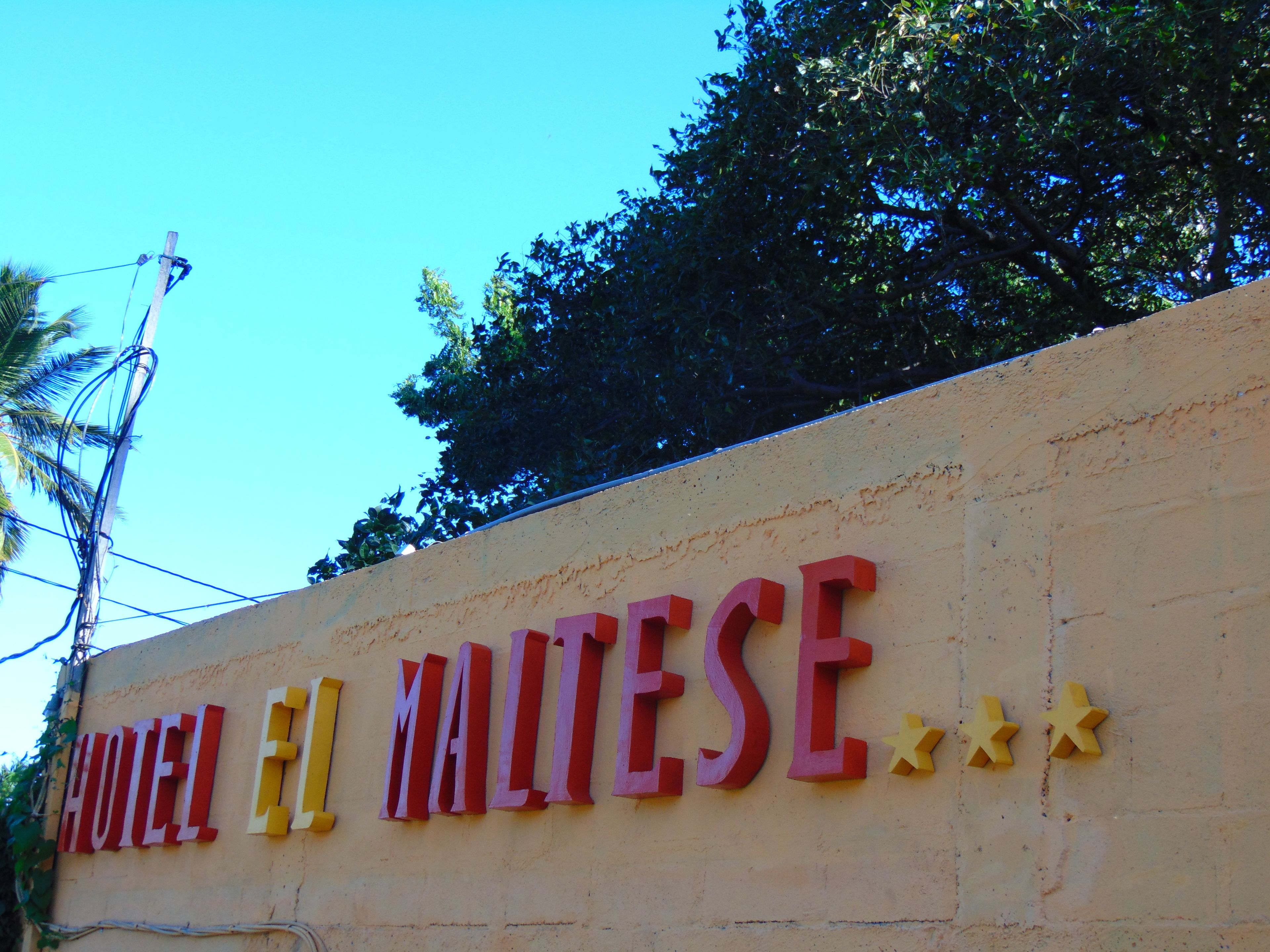 Une enseigne pour l’hôtel El Malese, avec de grandes lettres colorées et des décorations en forme d’étoiles.
