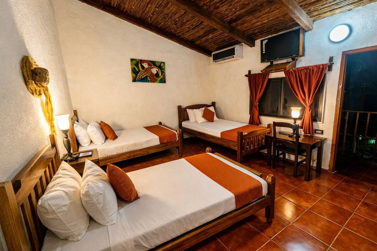 A room with two wooden beds, a wooden table, a chair, a TV, and a painting on the wall.