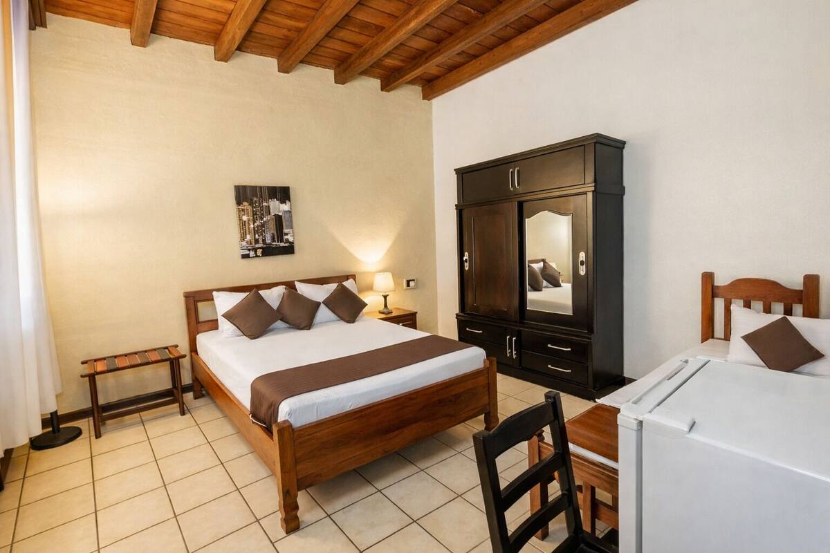 A bedroom with a wooden bed, a nightstand, a dresser, and a desk with a chair.