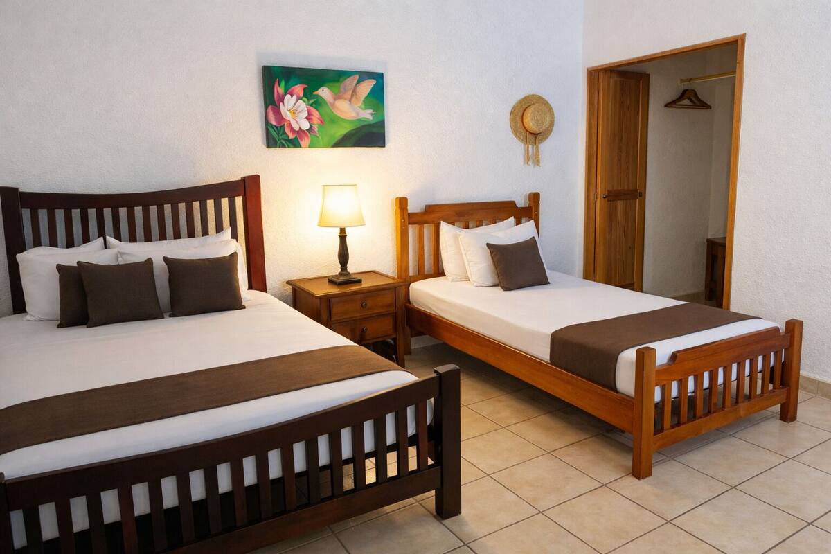 A double bed with a wooden headboard, a bedside table with a lamp, and a painting on the wall.