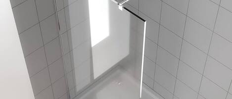 Un baño moderno con cabina de ducha de vidrio, paredes de azulejos blancos y suelo de tonos claros.