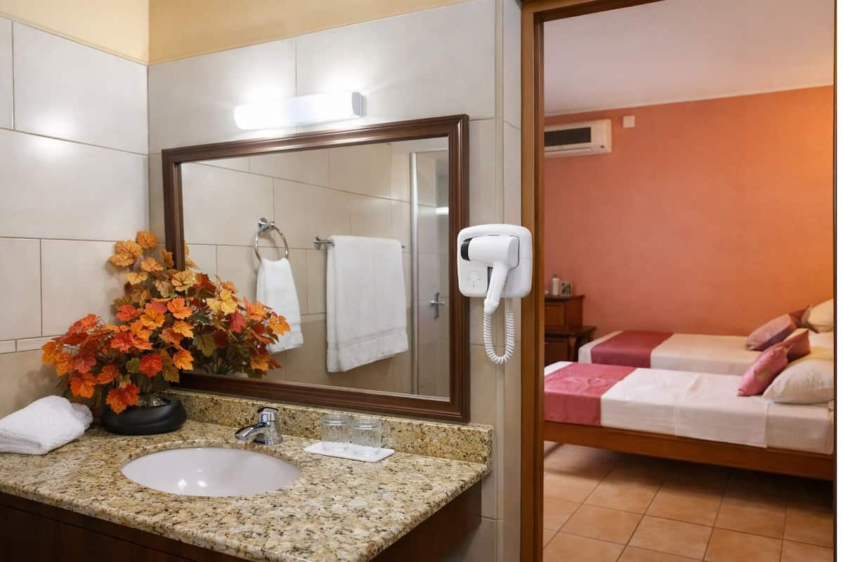 A bathroom with a sink, mirror, and a hairdryer on the wall.