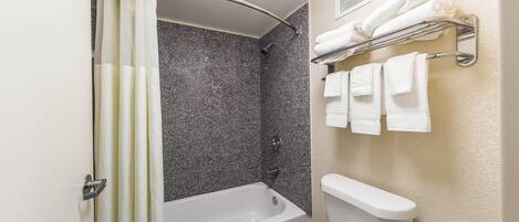 A bathroom with a bathtub, toilet, and towel rack.