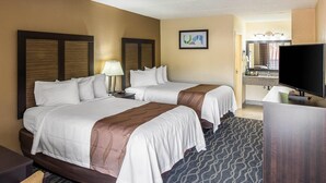 A hotel room with two beds, a desk, a TV, and a bathroom visible through an open door. - Quality Inn Forest City (Forest City)