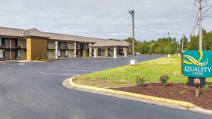 A Quality Inn with a parking lot, a grassy area with a sign, and a building with multiple rooms. - Quality Inn Forest City (Forest City)