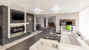 A modern living room with a fireplace, a sofa, a coffee table, and a TV mounted on the wall. - Quality Inn Forest City (Forest City)