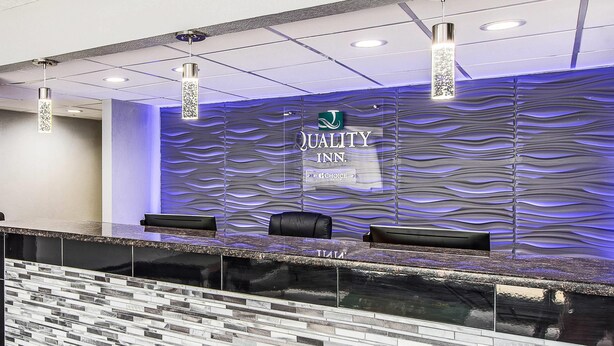 A reception area with a modern design, featuring a reception desk, seating, and a wall with a textured pattern. - Quality Inn Forest City (Forest City)