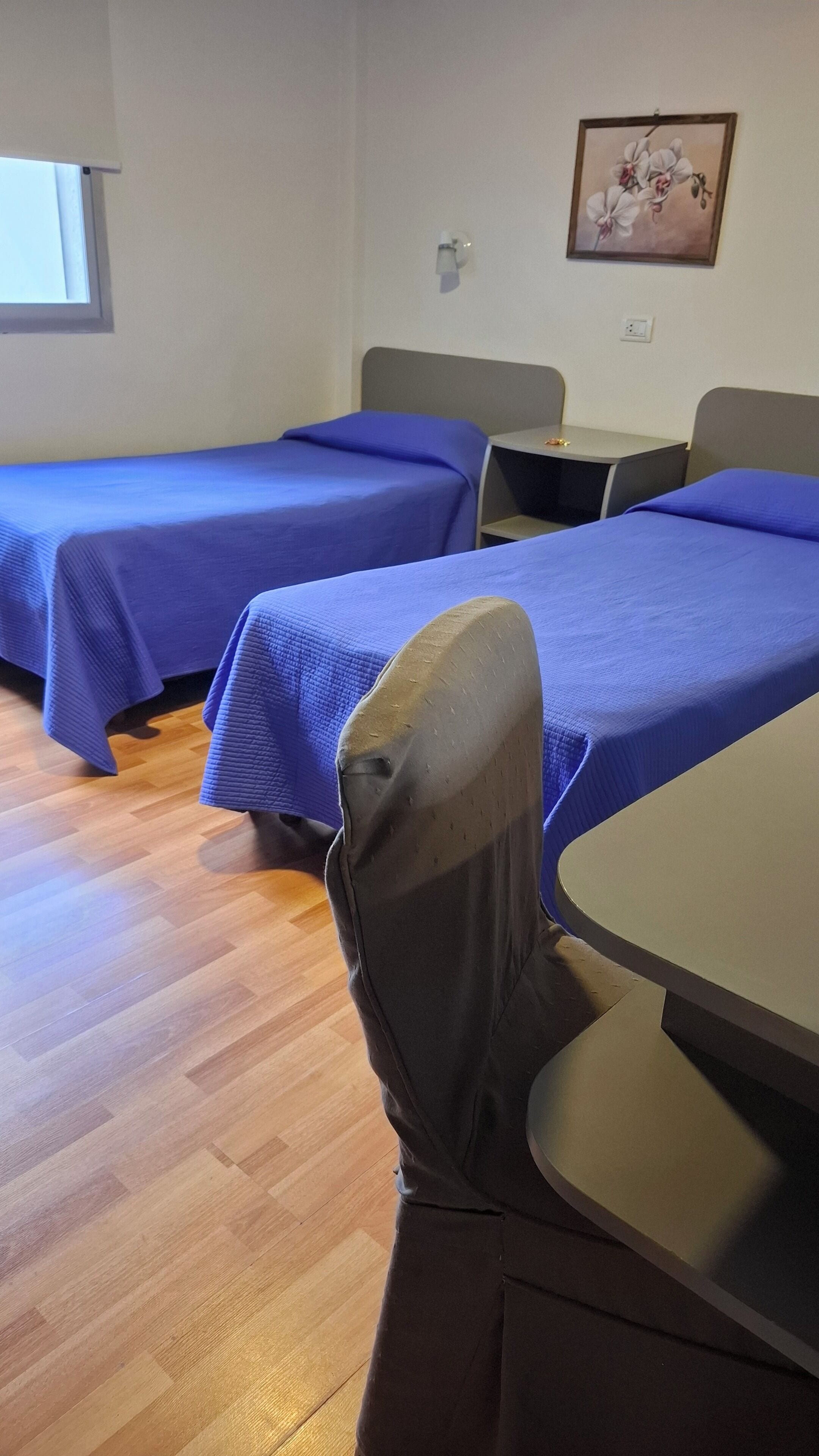 Une chambre d’hôtel avec deux lits simples, une petite table et une chaise.