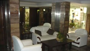 Un hall con sofás de cuero blanco, una mesa de centro oscura y un pilar grande.