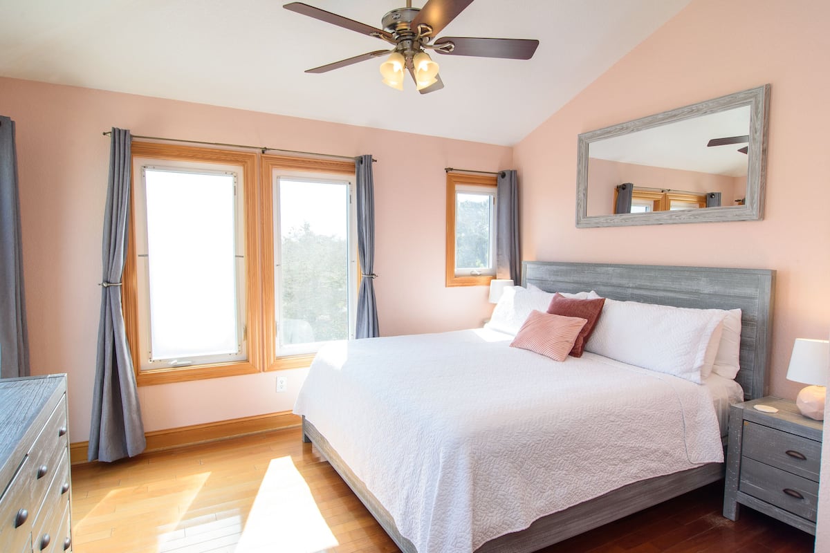 A bedroom with a bed, a nightstand, a dresser, and a ceiling fan.