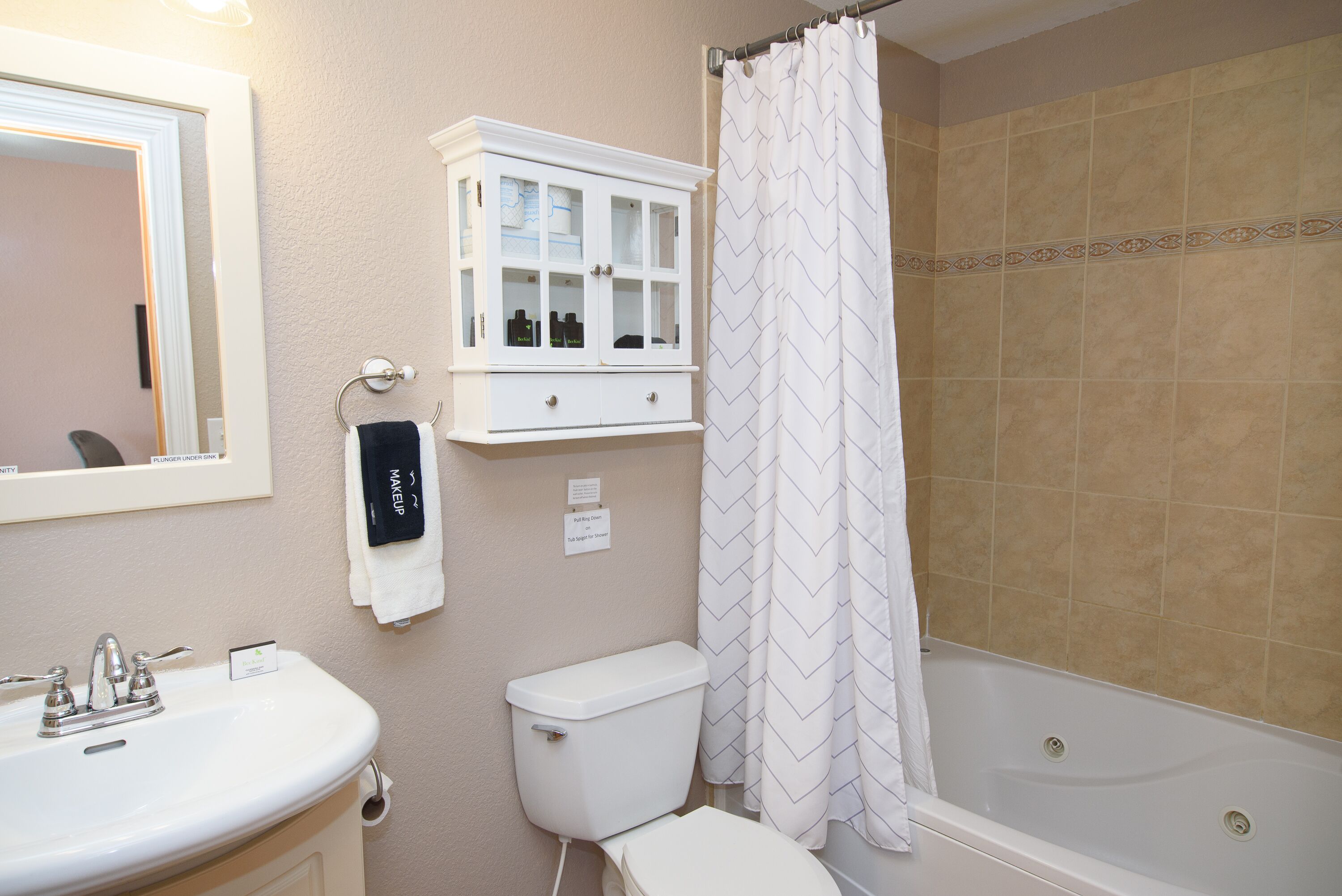 A bathroom with a sink, toilet, cabinet, and shower curtain.