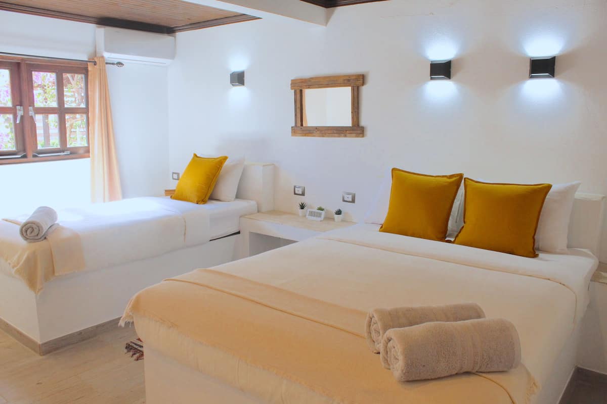 Una habitación de hotel con dos camas, una mesita y un espejo en la pared.